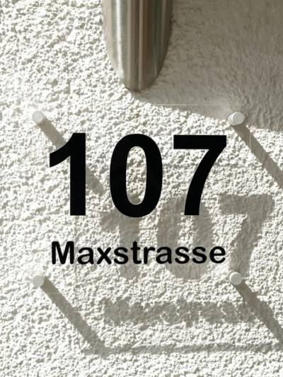 Hausnummer 3D in Schwarz mit Schattenwurf an Hauswand.