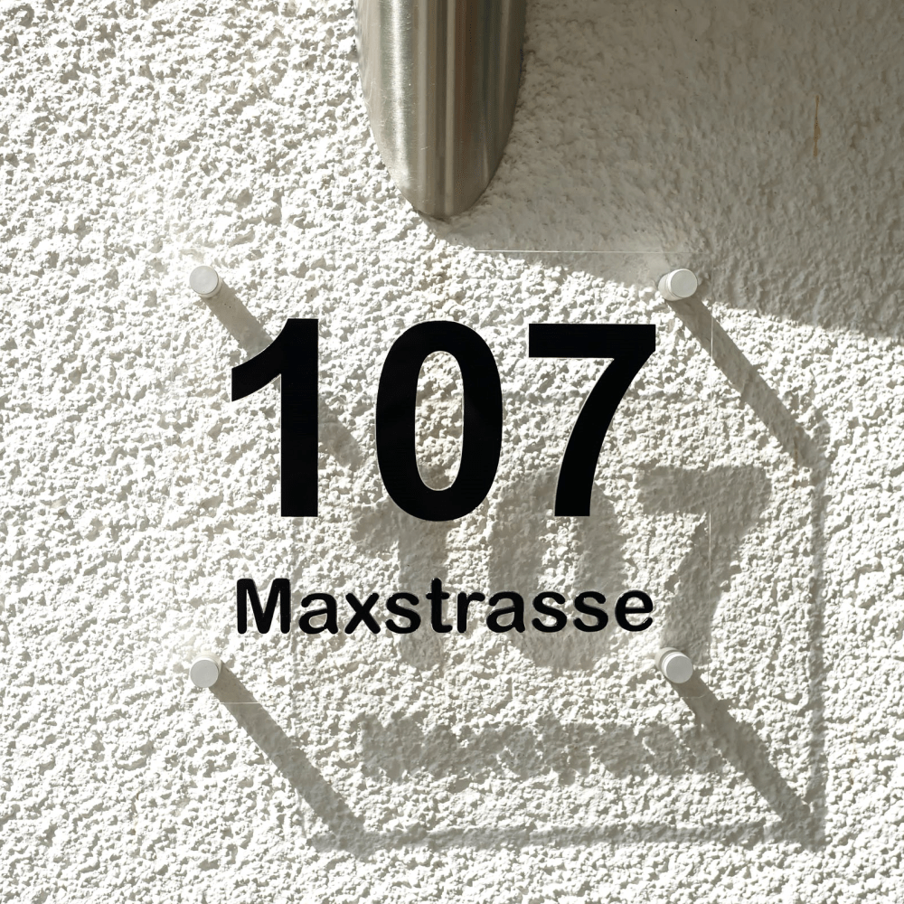 Hausnummer 3D in Schwarz mit Schattenwurf an Hauswand.
